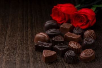 木目テーブルに並ぶ高級チョコレートのアソートと薔薇