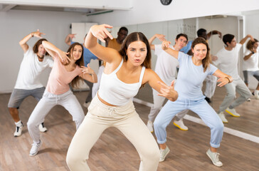 Group of positive dancers repeat dance in dance hall