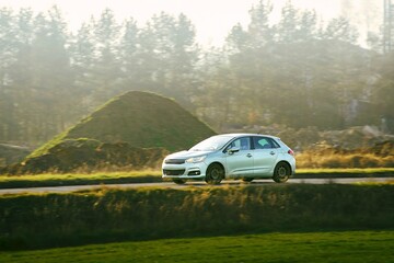 Modern hatchback driving on a road near trees drive on a sunny day