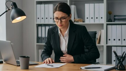 Woman Experiencing Stomach Pain at Office Desk Holding Abdomen - Powered by Adobe