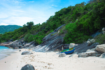 Tropical beach with soft sand and emerald water surrounded by lush green hills, captured in Cham...