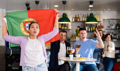 Fans with the flag of Portugal celebrate the victory of their favorite team in a beer bar