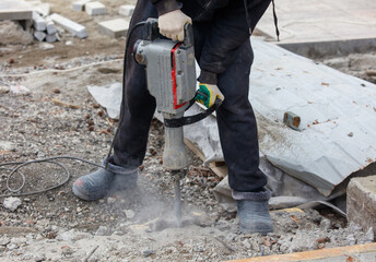 A man is using a jackhammer to break up concrete