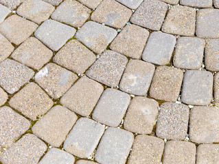 A brick walkway with a pattern of gray and tan bricks