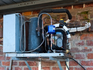 The refrigerator compressor is mounted on the wall of the building.