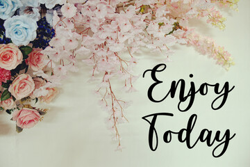 Enjoy Today text with flowers decorations on wooden background