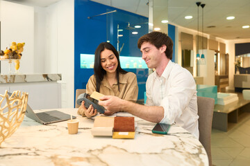 Couple designing home interior with advisor choosing materials in furniture showroom