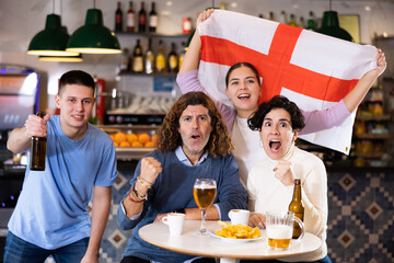 Group of happy people with England flag toasting with beer, having fun at party in nightclub