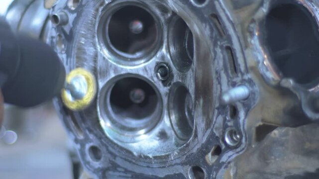 Engine Intake and Exhaust Valves. Close-up of motorbike engine cylinder head being cleaned with dremel tool,
