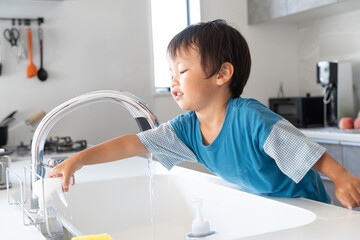 キッチンで家事のお手伝いをする子供