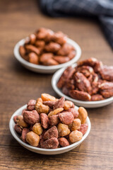 Nuts coated in sugar and honey in bowl on wooden table.