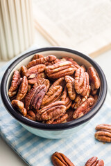 Peeled pecan nuts in bowl on white table.