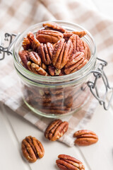 Peeled pecan nuts in jar on white table.