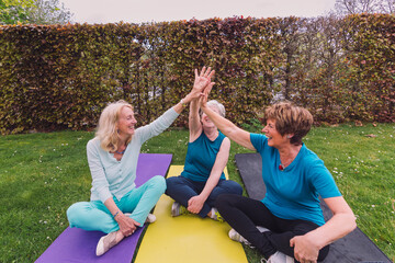 Senior women giving high five after yoga session in garden
