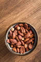 Nuts coated in sugar and honey in bowl on wooden table.