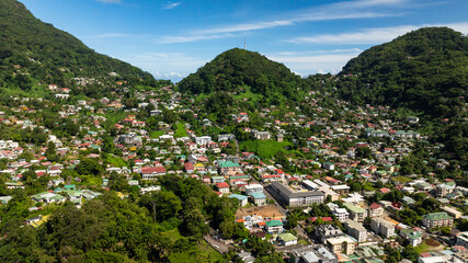City nestled within lush green hills under a clear blue sky. Victoria. Seychelles, Mahe.