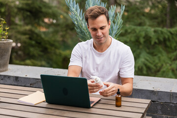 Man buying body products online using laptop in garden