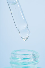 A drop of cosmetic oil falls from the pipette to the glass bottle. Skin care cosmetics design package. Hyaluronic or vitamin C serum for damaged skin