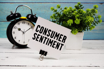 Consumer Sentiment text written on paper card with alarm clock on wooden background