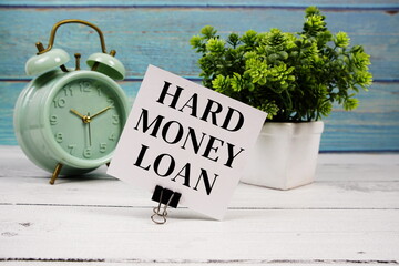 Hard Money Loan text written on paper card with alarm clock on wooden background
