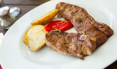Tasty beef steak with baked potatoes served at plate, spanish dish Churrasco a la plancha