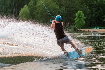 Wakeboarder making tricks. Low angle shot of man wakeboarding on a lake. Man water skiing at sunset.