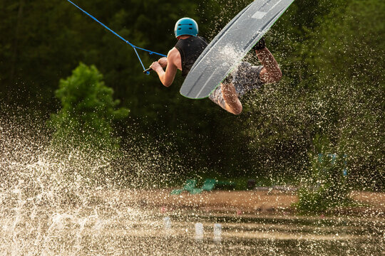 Wakeboarder making tricks. Low angle shot of man wakeboarding on a lake. Man water skiing at sunset.	
