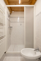 Renovated modern bathroom interior in an old, typically Italian building with a wooden ceiling.