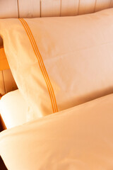 Detail of a bed where one can practically only see the pillow illuminated by a red-yellow light. Very cozy