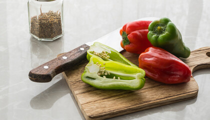 knife and green and red peppers on the cutting board