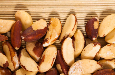 Natural background of shelled roasted Brazil nuts on light wood surface. Healthy snack..