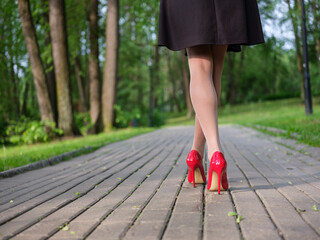 women's legs in stiletto heels on a path in the park