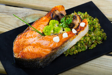 Dish of tasty steak of fried salmon with broccoli served on plate at table