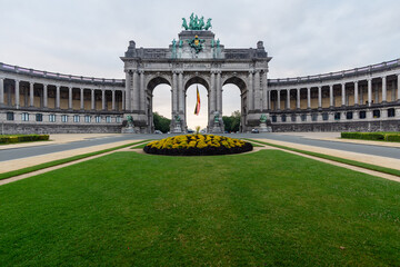 Low angle shot of the Cinquantenaire Arcade with yellow flowerbed and grass field