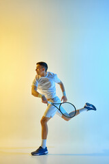 Naklejka premium Stylish tennis player completing swing step with focused expression against colored blue-yellow gradient background in warm neon light. Concept of sport event, match, preparation, action