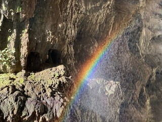 A brilliant rainbow glowing against the rugged cliff