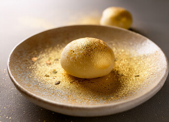 goldenes Mochi auf einem runden teller mit Goldstaub