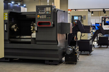 Modern dark gray CNC lathe machine in an industrial setting, featuring control panel, chuck, and parts catcher. Symbolizes precision manufacturing and automation technology in factory