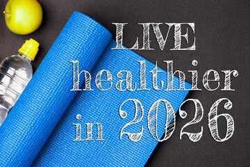 New year 2026 resolutions healthy lifestyle and sport. Be healthy in 2026. Motivation sport goals 2026 with sport equipment shoes, dumbbells, fruit and water bottle on black background