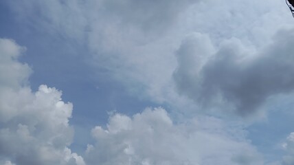 Obraz premium A serene blue sky adorned with fluffy white and gray clouds, creating a peaceful, expansive natural scene.