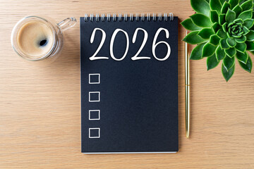 New year resolutions 2026 on desk. 2026 goals list with notebook, coffee cup, plant on wooden table. Resolutions, plan, goals, action, checklist, idea concept. New Year 2026 resolutions. Copy space