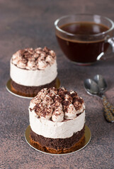 Two portions of cake Tiramisu and coffee on brown background