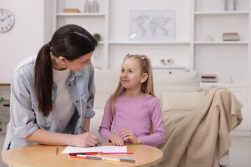 Fototapeta premium Mother teaching her daughter to draw at table indoors, space for text