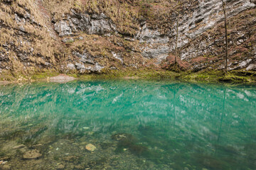 piccolissimo lago naturale di montagna in Slovenia, con sorgente sotterranea e acqua cristallina e piatta, color verde smeraldo, di giorno, in inverno - obrazy, fototapety, plakaty