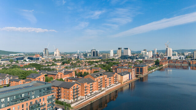 Aerial drone photo of Bute East Dock and the Atlantic Wharf neighbourhood in Cardiff, Wales, with a panoramic view of the city centre in the background. 