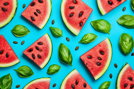 Fresh watermelon slices and basil leaves create a vibrant pattern on a bright blue background. - Powered by Adobe