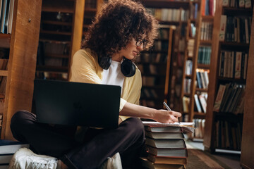Working by using laptop. Beautiful woman is in the library