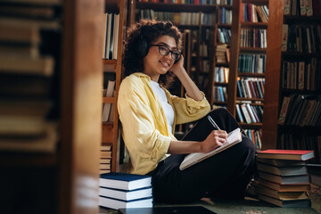 Listening to music and writing. Beautiful woman is in the library