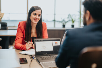 A woman in a red blazer engages in a professional discussion during a business meeting in an office...