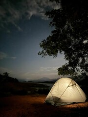 Night camping with tent under starry sky.